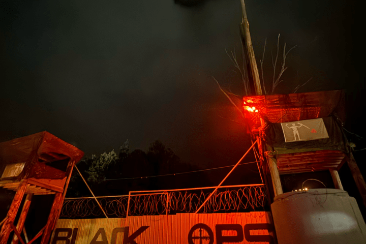 Night scene at 'Black Ops' entrance with red lights and watchtower.